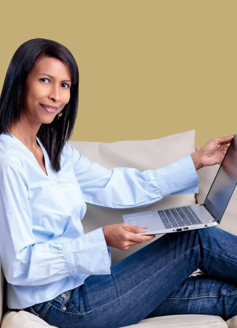 Mentoría 7 imagen de una joven sentada mirando su laptop y trabajando con alegría y entusiasmo después de haber recibido su sesión de mentoría personalizada
