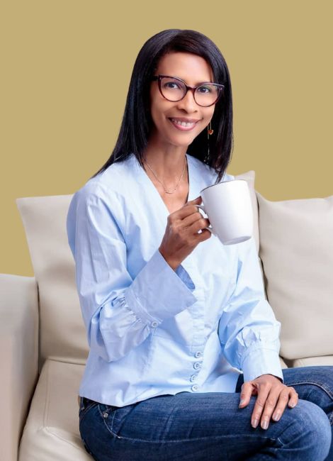 Mentoría 8 una joven sentada con una taza de café en la mano con alegría y entusiasmo porque después de su sesión de mentoría vive con propósito y gestiona bien sus emociones.